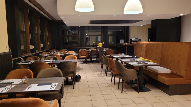 Een modern restaurant met gezellige stoelen en tafels. De verlichting is vriendelijk en zorgt voor een uitnodigende sfeer.