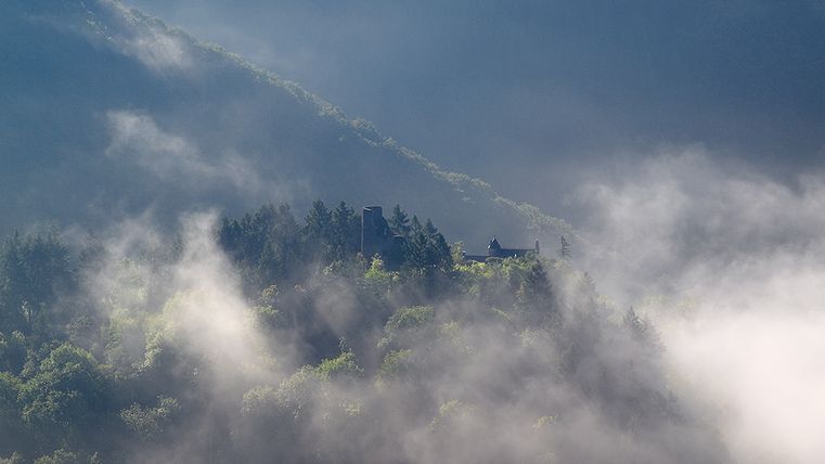 Falkenstein Castle in the fog on a wooded hill.