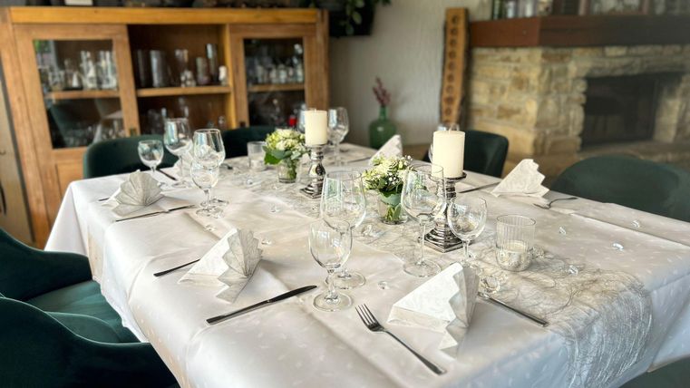An elegantly set table with glassware and flowers. The table is decorated with a white tablecloth and stylish napkins.