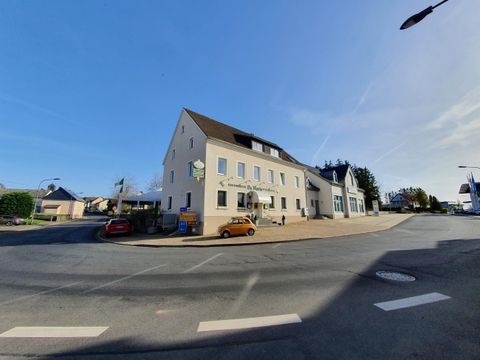 Een modern gebouw op een straathoek met een heldere lucht op de achtergrond. Op straat staan enkele auto's geparkeerd.