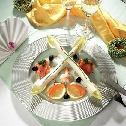 An elegantly arranged plate with seafood, smoked salmon, and lemon slices. Accompanied by a glass of wine and decorative napkins.