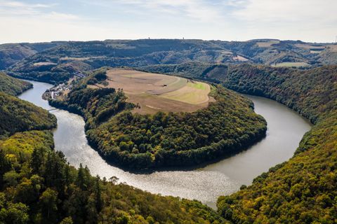 Aerial view of a river bend in a wooded landscape with fields.