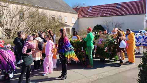 Un groupe de personnes en costumes colorés se rassemble dans une rue. Il semble y avoir une fête joyeuse ou un défilé.