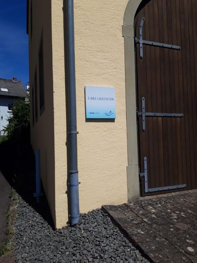 Une station de recharge pour vélo électrique sur un mur. La station est bien visible et accueillante.