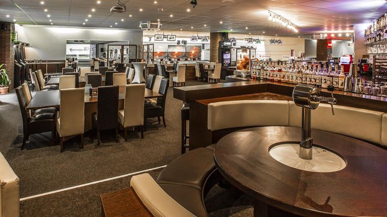 Een modern restaurant met elegante tafels en stoelen. De sfeer is uitnodigend, met inrichting en verlichting die een gezellige ambiance creëren.