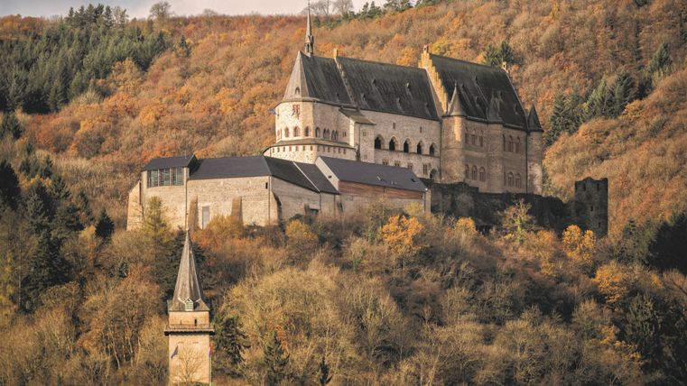 Schloss Vianden inmitten herbstlicher Bäume.