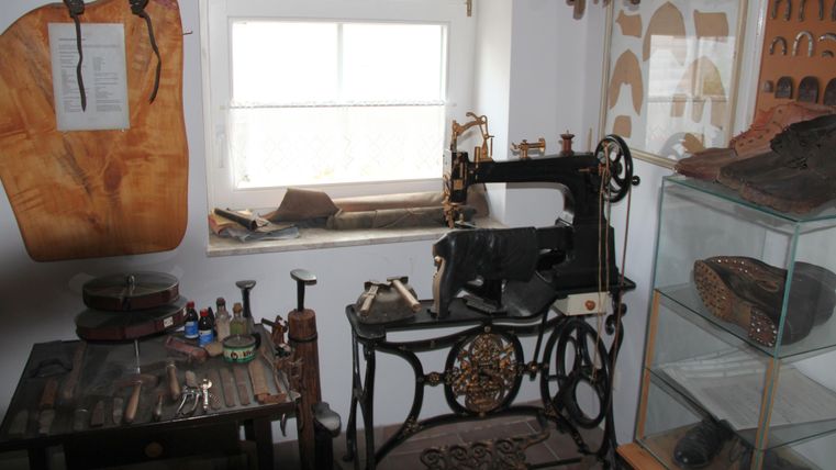A historic tailor's room with a sewing machine from the past. On the table, tools and materials for tailoring can be seen.
