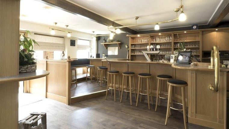 A modern bar with wooden furniture and high seating. The decor is bright and inviting, perfect for social gatherings.