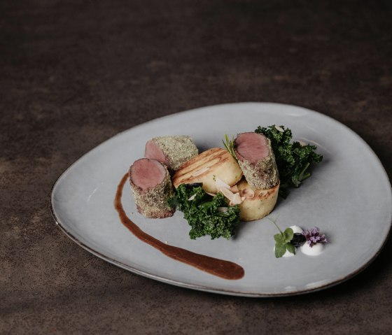 Dos de chevreuil rôti rose en croûte d'herbes et de verdure
