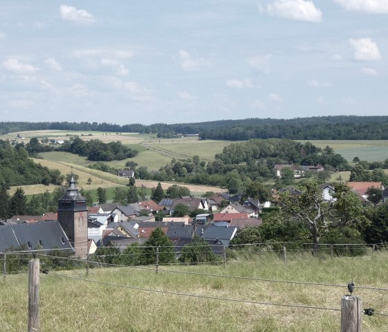 Vue panoramique de Gransdorf avec une &eacute;glise au premier plan, entour&eacute;e de maisons et d'un paysage verdoyant sous un ciel bleu., &copy; TI Bitburger Land