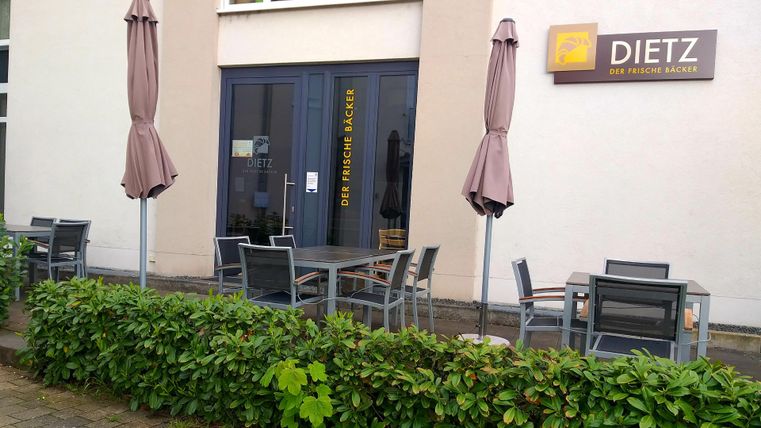An outdoor area of a restaurant with tables and chairs. Some umbrellas are on the terrace.