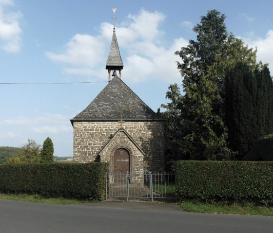 Chapelle en pierre avec toit pointu et girouette, entour&eacute;e d'arbres et de haies, sur fond de ciel bleu., &copy; Conny Meier