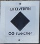 Balisage de sentier de randonn&eacute;e de l'Eifelverein avec un losange noir et l'inscription 'OG Speicher' sur fond blanc.