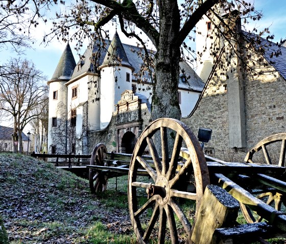 Le ch&acirc;teau de Rittersdorf en hiver, entour&eacute; d'arbres d&eacute;nud&eacute;s. Au premier plan, de vieilles roues de wagons en bois qui cr&eacute;ent une atmosph&egrave;re historique., &copy; TI Bitburger Land