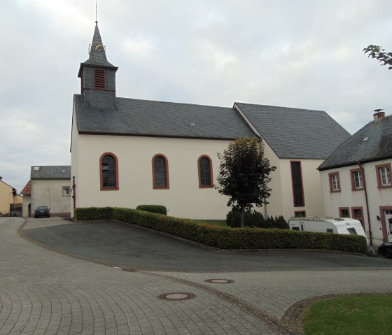 L'&eacute;glise St. Urban &agrave; Gindorf avec sa tour caract&eacute;ristique et les b&acirc;timents environnants. Une caravane se trouve &agrave; c&ocirc;t&eacute; de l'&eacute;glise., &copy; Conny Meier