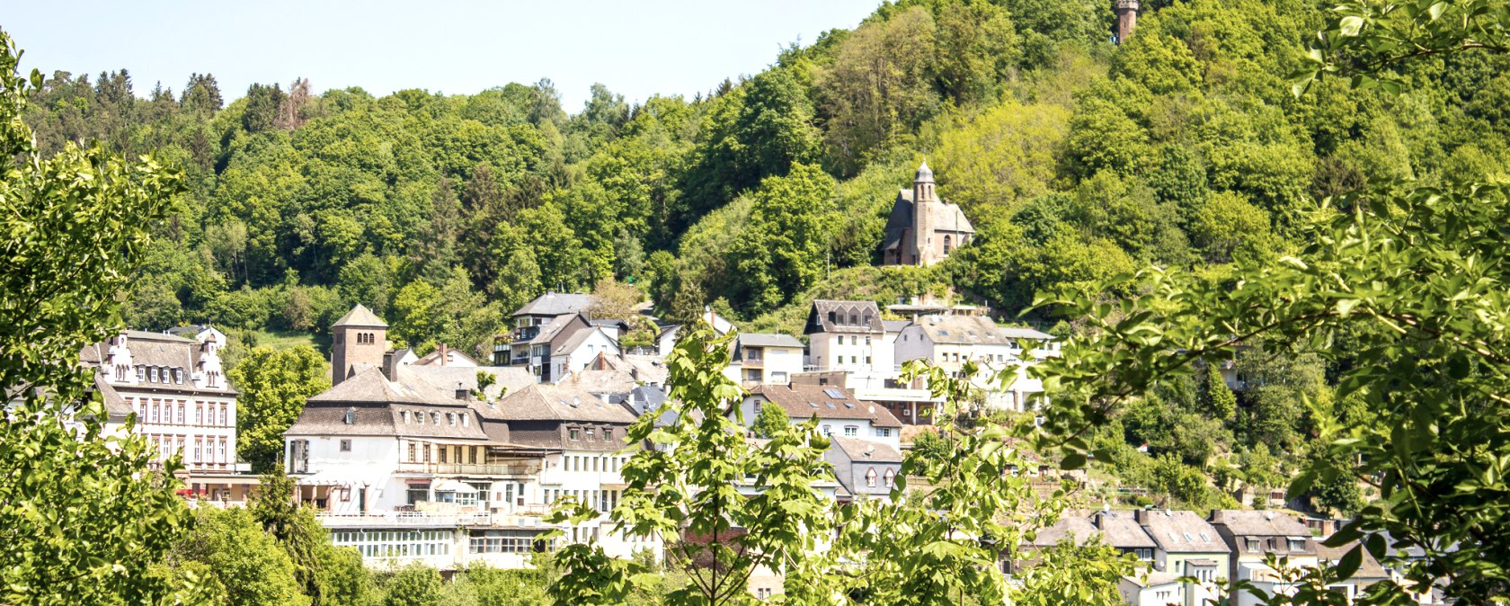 Gezicht op Kyllburg met historische gebouwen en een kerk, omringd door dichtbeboste heuvels onder een blauwe hemel., &copy; Tourist-Information Bitburger Land_Monika Mayer