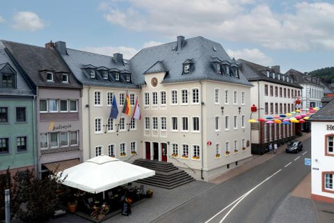 A modern building with flags and colorful decorations. The street view shows an inviting atmosphere with an outdoor table.