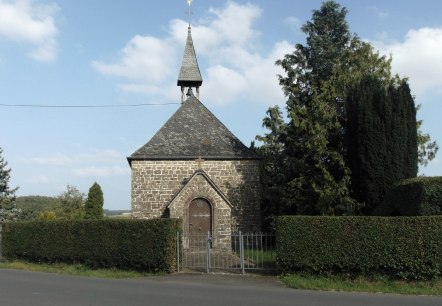 Chapelle en pierre avec toit pointu et girouette, entour&eacute;e d'arbres et de haies, sur fond de ciel bleu., &copy; Conny Meier