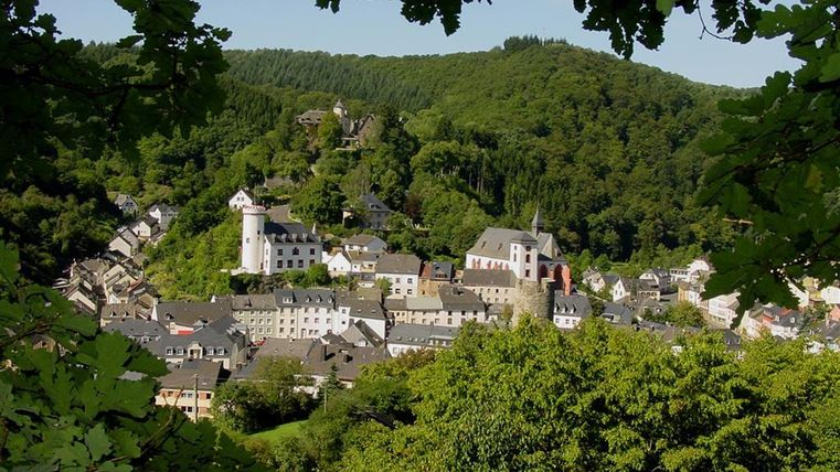A picturesque town surrounded by green hills. In the background, ancient castles and historical buildings can be seen.