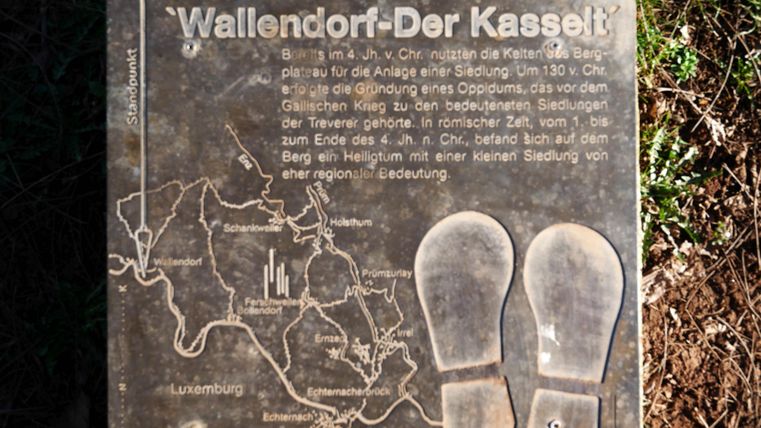 Un panneau d'information sur Wallendorf-Der Kasselt, qui montre une carte et des empreintes de pas. Il décrit l'importance historique de la région et son histoire de peuplement.