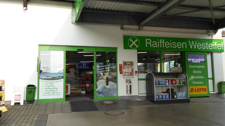 Een markt met een ingangsgebied in groene kleuren. Er zijn reclameborden en planken zichtbaar die verschillende producten tonen.