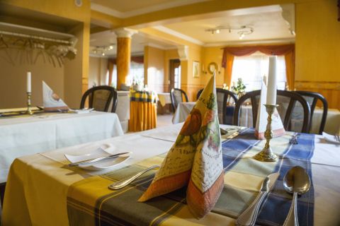 An elegant restaurant with beautifully set tables. The tables are decorated with cloth napkins and candles.