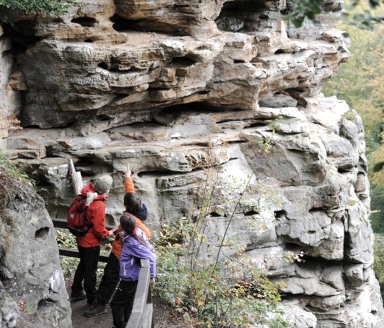 Drie wandelaars op een pad in de Devil's Gorge, kijken naar en wijzen naar indrukwekkende rotsformaties., &copy; Felsenland S&uuml;deifel Tourismus GmbH