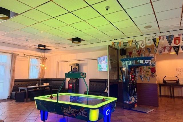 A cozy room with an air hockey table and a TV on the wall. Pennants hang from the ceiling, creating a sporty atmosphere.