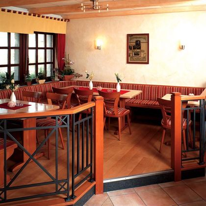 A cozy restaurant with wooden tables and benches. The walls are painted in warm colors and the lighting is soft.