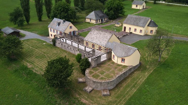 Une ferme pittoresque avec plusieurs bâtiments et un grand terrain verdoyant. Entourée d'arbres et de prairies, elle offre une impression de tranquillité rurale.