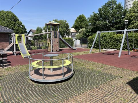 Vue frontale des équipements de jeux, tour d'escalade, balançoire et manège.