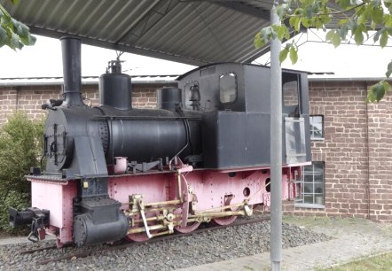 Eine alte Dampflokomotive steht unter einem Schutzdach vor einem Backsteingeb&auml;ude. Die Lokomotive ist schwarz und rosa gestrichen., &copy; Eifelverein Ortsgruppe Speicher