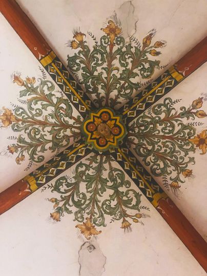 A picturesque ceiling design featuring floral motifs in various colors. The ornaments are detailed and harmoniously arranged.