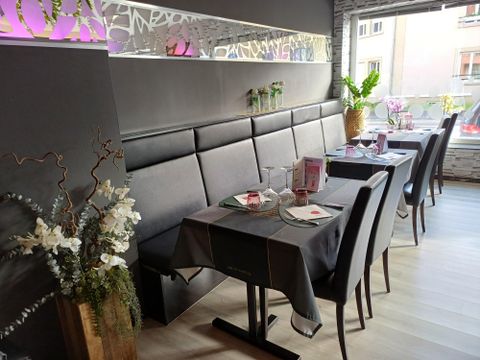 A modern restaurant with elegant tablecloths and decorative flowers. The walls are adorned and the atmosphere is inviting.