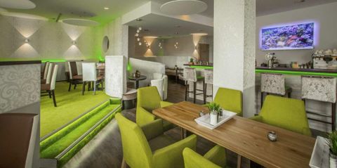 Een modern restaurant met groene stoelen en een stijlvolle ambiance. De inrichting is licht en uitnodigend, ideaal voor een ontspannen maaltijd.