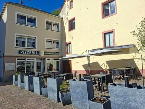 Een pizzeria met buitenruimte in een charmante straat. Tafels en stoelen zijn onder parasols geplaatst.