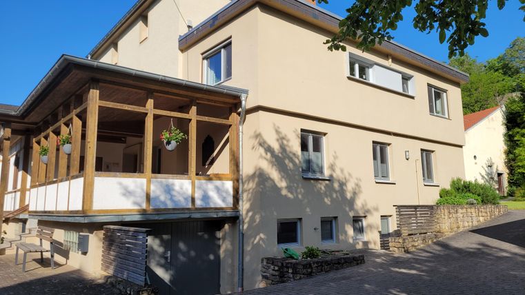 A modern house with a covered entrance area and plenty of daylight. The surroundings are green and inviting.