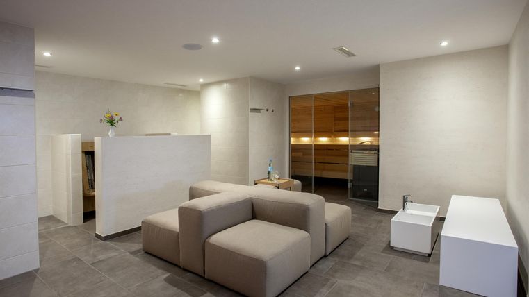 A modern living room with a beige sofa and a bright, minimalist design. The walls are light, and the lighting is pleasant.