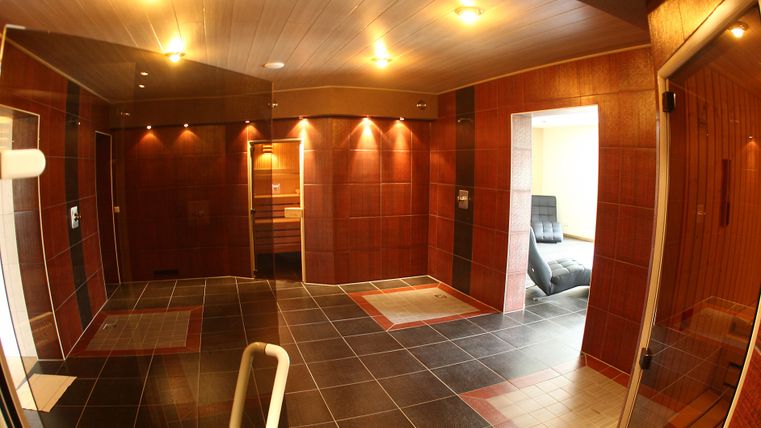 A modern wellness area with wood paneling and soft lighting. The room is empty and offers space for relaxation and rejuvenation.