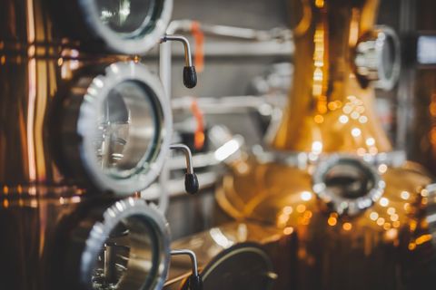 Eine detailreiche Ansicht von Kupferdestillieranlagen. Die glänzenden Oberflächen und präzisen Maschinen vermitteln ein handwerkliches Ambiente.