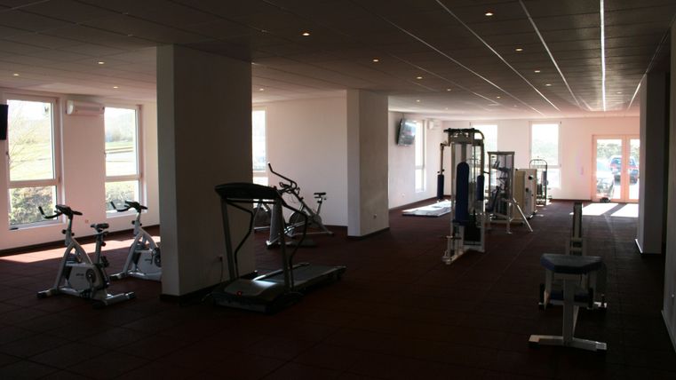 A modern gym with various training equipment. Plenty of space and large windows create a bright, inviting atmosphere.