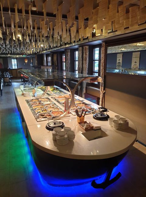 An elegant buffet in a refined restaurant. It showcases a variety of dishes on a white table with soft lighting.