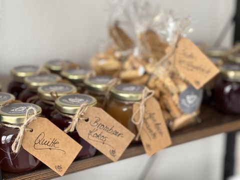 Een liefdevol samengestelde selectie van mason jars met verschillende jam en koekjes. Elk glas is voorzien van een handgeschreven label.