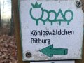 Schild mit der Aufschrift 'K&ouml;nigsw&auml;ldchen Bitburg' und einem gr&uuml;nen Pfeil nach links. Im Hintergrund sind B&auml;ume und Laub zu sehen., &copy; TI Bitburger Land