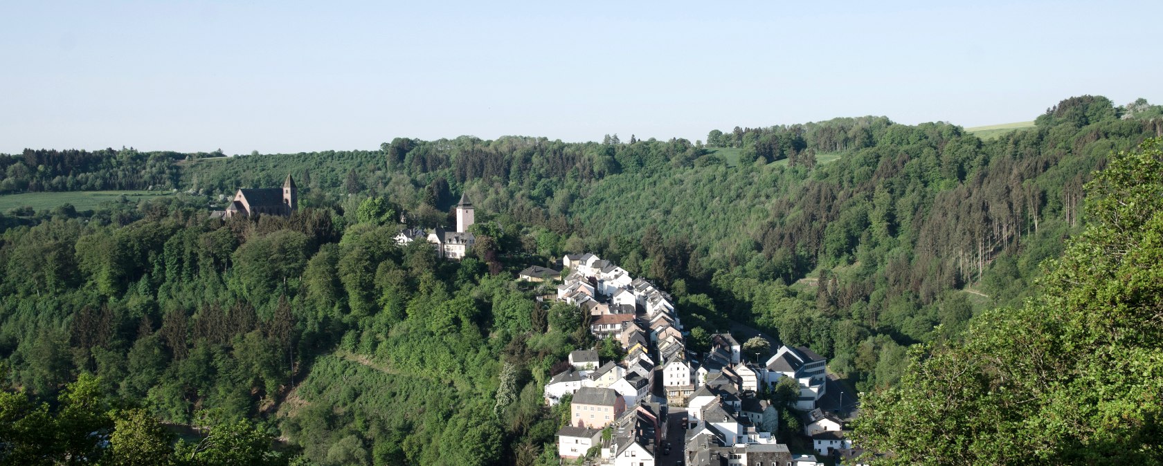 Vue panoramique de Kyllburg avec son &eacute;glise et ses maisons, nich&eacute;e dans des for&ecirc;ts et des collines verdoyantes sous un ciel d&eacute;gag&eacute;., &copy; TI Bitburger Land