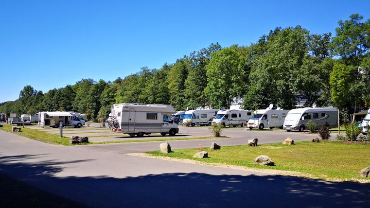 A quiet campsite with several motorhomes and plenty of green space. The atmosphere is peaceful and inviting.