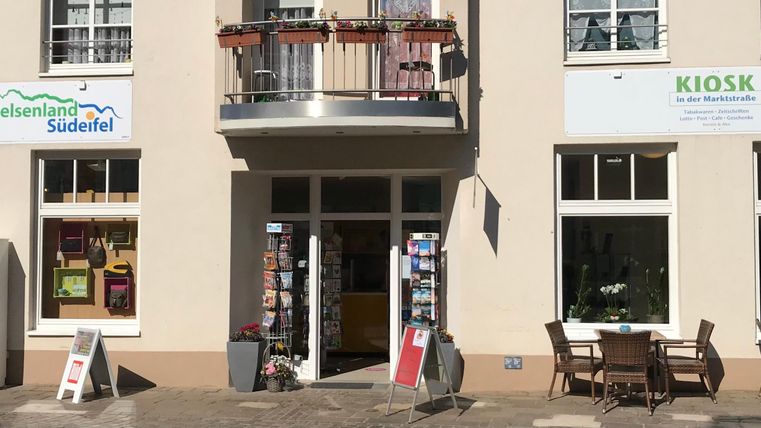 A friendly store with a kiosk and an information center. Outside, there are tables and chairs for guests.