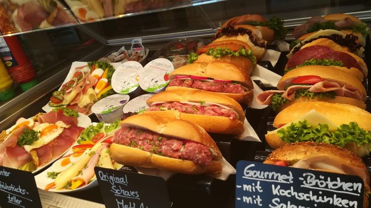 Une variété de sandwiches frais et de charcuterie dans une vitrine. Le choix comprend différentes garnitures et petits pains, joliment présentés.