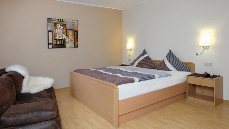 A cozy room with a double bed and modern pillows. A couch and a bedside table complement the relaxed atmosphere.