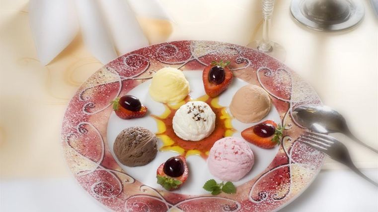 A plate with seven different types of ice cream and fresh fruits. The colors and shapes make the dessert appetizing and inviting.